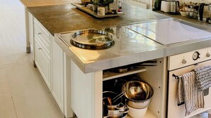 Une cuisine spacieuse dotée d’un grand îlot central, de meubles blancs et offrant une vue sur l’extérieur.