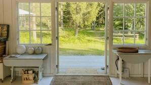 Une pièce avec un plancher en bois, un banc, une table et une grande fenêtre donnant sur un paysage verdoyant.