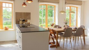Une cuisine dotée d’un îlot central, de chaises en bois et de luminaires suspendus.