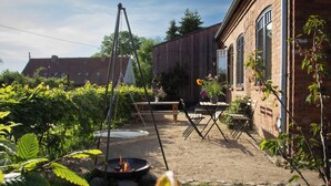 Un jardin avec un foyer extérieur, des sièges de jardin et un bâtiment en briques.