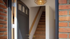 Un escalier en bois, avec un mur blanc d’un côté et un mur en briques de l’autre.