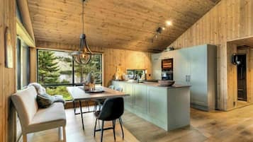 Une cuisine moderne dotée d’un îlot central, de meubles de rangement en bois et d’un coin repas avec une banquette et des chaises.
