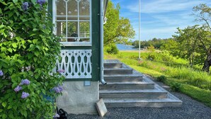 Un bâtiment vert avec une fenêtre blanche et une clôture en bois peinte en blanc.