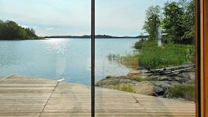 Eine Holzstege, der zu einem ruhigen See mit bewaldetem Ufer führt.