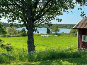 Ländliche Landschaft mit Baum, Heuballen und einem Holzhaus.