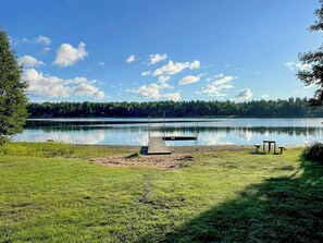Un cadre paisible au bord du lac, avec un quai, une pelouse et un banc.