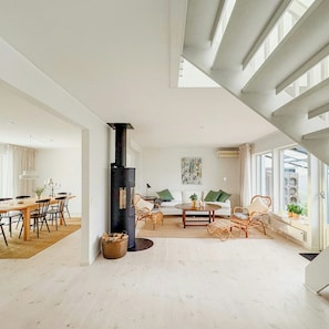 Ein geräumiger Wohnbereich mit hohen Decken, einem Kamin, einem Esstisch und einer Couch.