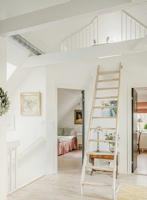 Ein mehrstöckiges Interieur mit einer Holzleiter, einer Treppe und einem Bett im Hintergrund.