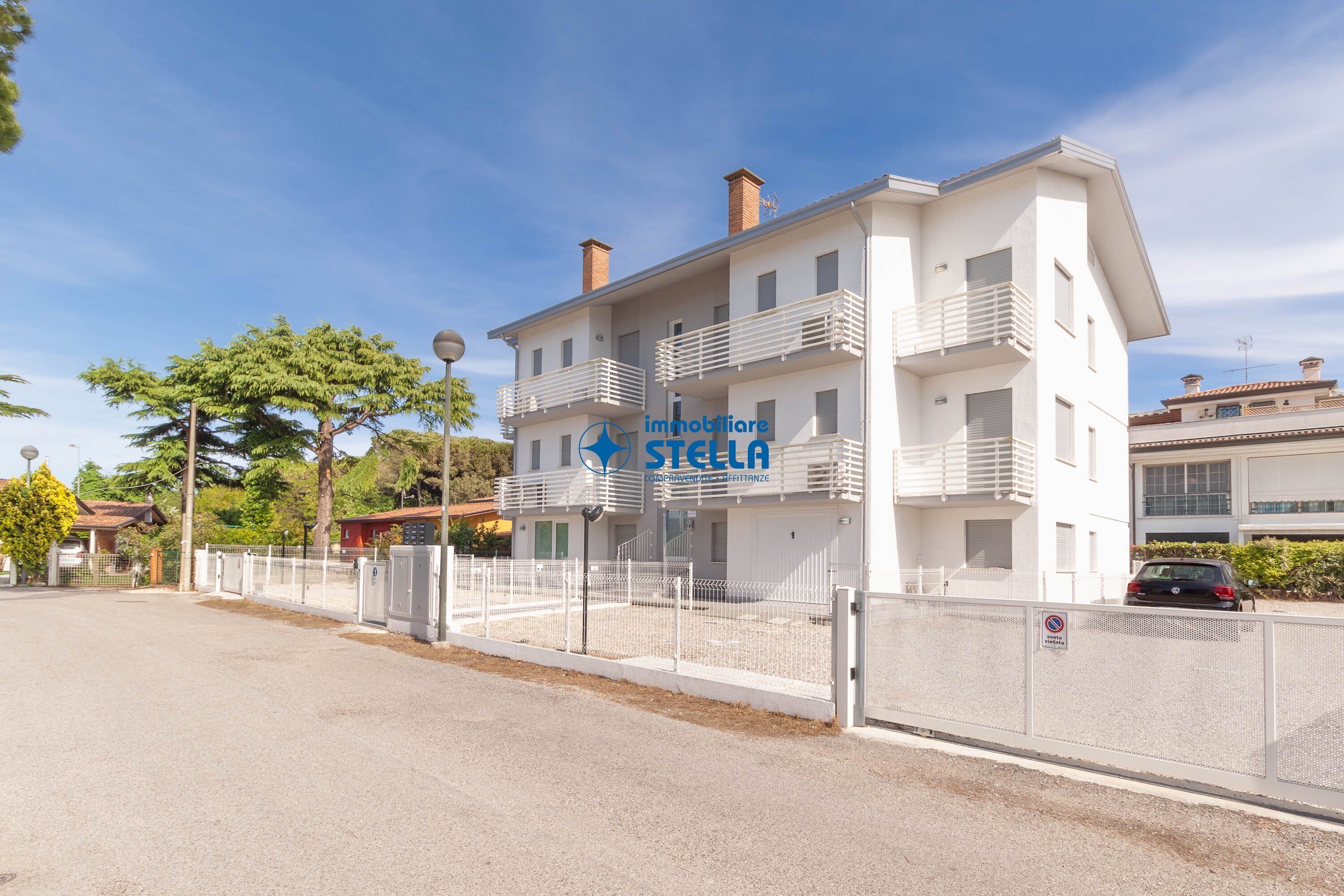 Un edificio a più piani con facciata bianca, balconi e un cartello con la scritta 'immobiliare STELLA'.