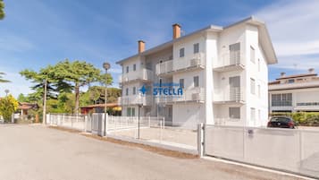 Un edificio a più piani con facciata bianca, balconi e un cartello con la scritta 'immobiliare STELLA'.