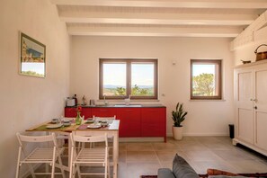A kitchen with red cabinets, a dining table with chairs, and a view of the outdoors through large windows. - Flat with views in Belvedere (Belvedere Ostrense)