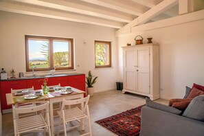 A kitchen with a dining table, chairs, a red cabinet, and a white cabinet. - Flat with views in Belvedere (Belvedere Ostrense)