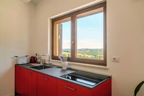 A kitchen with a window, red cabinets, a sink, and a toaster. - Flat with views in Belvedere (Belvedere Ostrense)