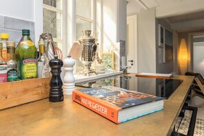 Eine Küchenarbeitsplatte mit einem Buch mit dem Titel 'Mad og Gæster', einem Pfeffermahlwerk und verschiedenen Flaschen.