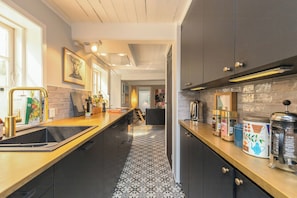 Eine moderne Küche mit einem schwarz-weißen Fußboden, einer Holz Arbeitsplatte und verschiedenen Küchengeräten sowie Stauraumschränken.