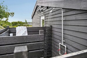 A wooden structure with a water feature, including a pipe and a spout. - Outdoor life in holiday home at Dråby Strand (Ebeltoft)