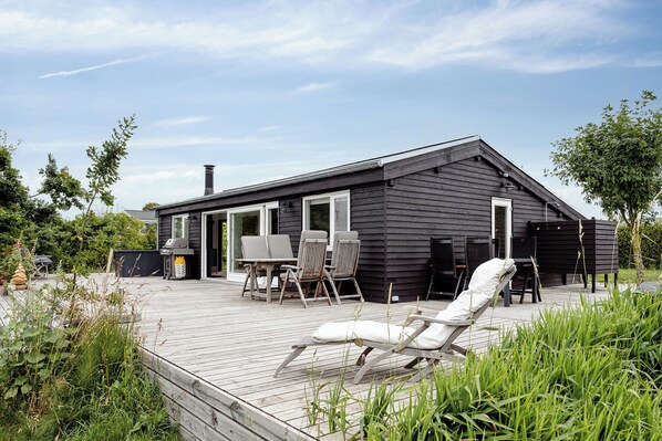 A modern house with a deck, outdoor seating, and a grill area. - Outdoor life in holiday home at Dråby Strand (Ebeltoft)