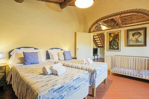 Ein Schlafzimmer mit zwei Betten, einem Babybett und einer Treppe zu einer erhöhten Ebene.