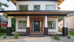 A two-story house with a front porch, large windows, and a dark front door.
