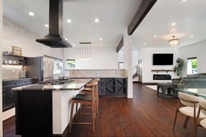 Una cocina moderna con una isla grande, piso de madera oscura y televisor integrado.