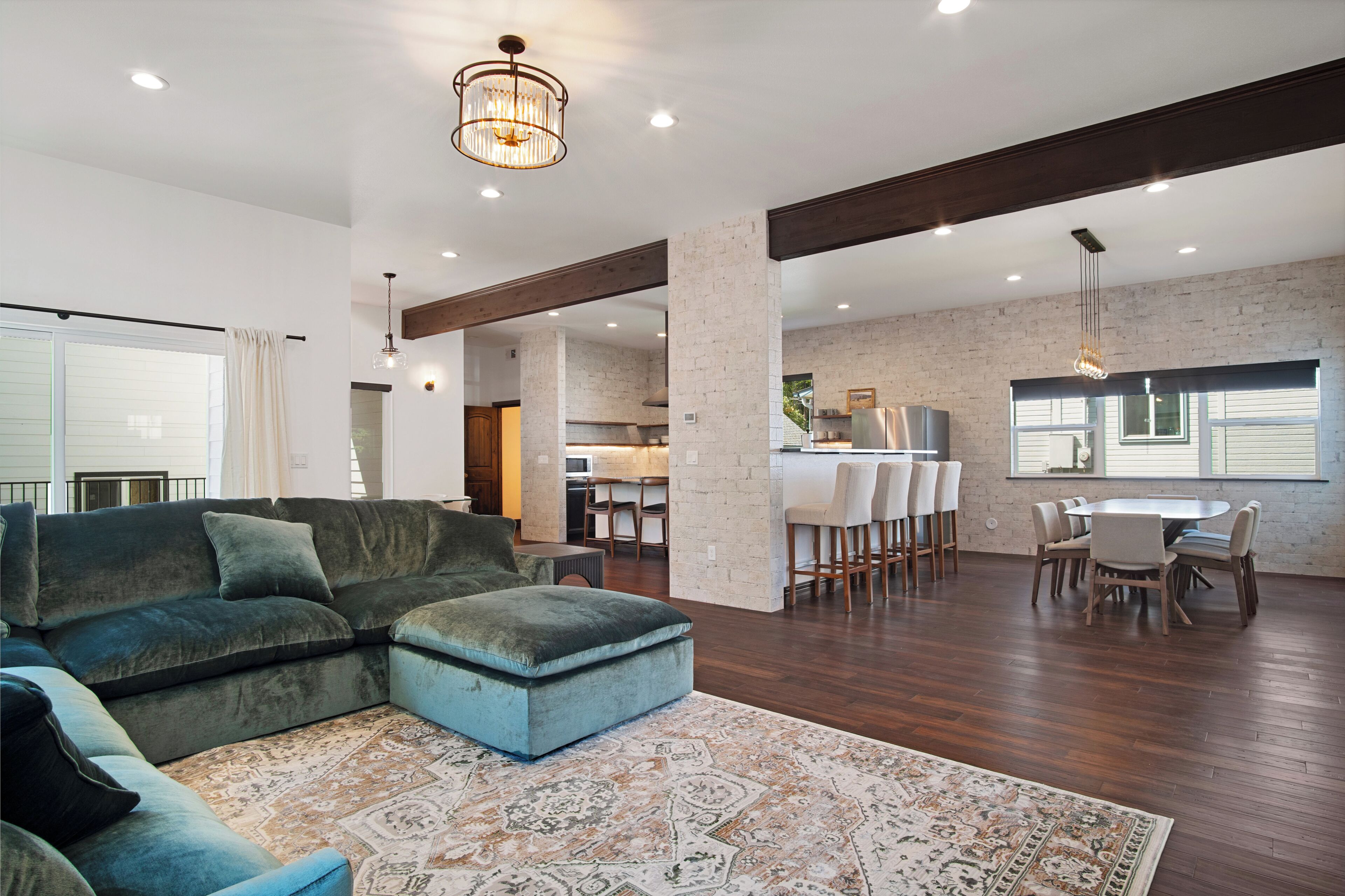 A spacious living area with a sectional sofa, a dining table with chairs, and a kitchen in the background.