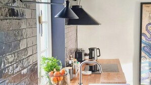A modern kitchen with a wooden countertop, black pendant lights, a sink, and a window. - Maritime holiday home secluded on the dike (Osterhever)