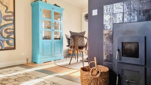 A room with a blue cabinet, a patterned chair, a woven basket, and a fireplace. - Maritime holiday home secluded on the dike (Osterhever)