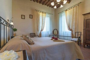 Ein Schlafzimmer mit einem Bett, zwei Stühlen, einem Holzschrank und einer Deckenleuchte.