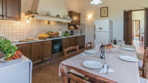 Una cocina con armarios de madera, una mesa de comedor preparada para cuatro personas y un refrigerador.