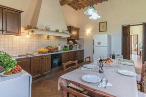Eine Küche mit Holzausstattung, einem Esstisch für vier Personen und einem Kühlschrank.