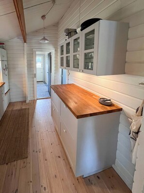 Ett kök med träskåp, en bänkskiva i trä och ett kylskåp.