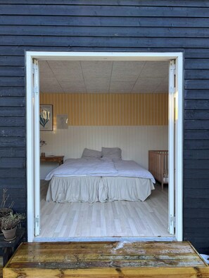 A bedroom with a bed, a nightstand, a crib, and a potted plant. - Family summer house near plantation and beaches (Højby)