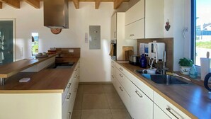Una cocina moderna con vigas de madera, electrodomésticos de acero inoxidable y vistas al exterior.