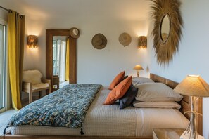 A bedroom with a bed, pillows, a lamp, a mirror, and a chair. - Secluded villa with sea view in Palombaggia (porto vecchio)