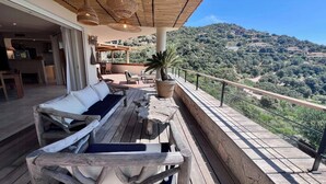 Una terraza de madera con un sofá, una mesa y una planta en maceta.