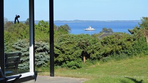 Une vue d’un bateau sur une étendue d’eau, entouré de verdure et sous un ciel dégagé.