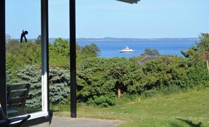 A view of a boat on a body of water, surrounded by greenery and a clear sky. - Family house with sea view by Lynæs beach (Hundested)
