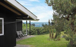 A building with a covered patio, two chairs, and a view of the sea. - Family house with sea view by Lynæs beach (Hundested)