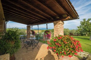 A covered patio with brick columns, outdoor furniture, and a view of the countryside. - Ground floor apartment by Lake Trasimeno (Castiglione del Lago)