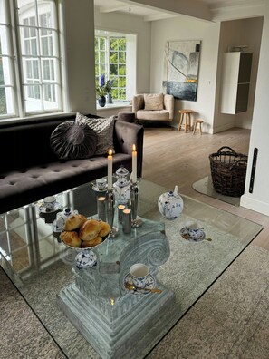 A modern living room with a glass coffee table, a sofa, and a view of the outdoors. - Historic beach villa with pool at Marielyst (Væggerløse)