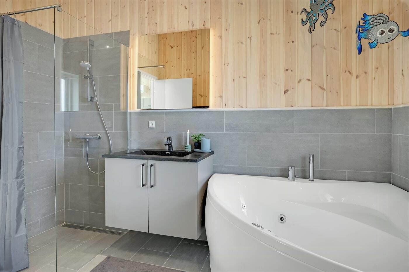Un bagno moderno con doccia a parete in vetro, una vasca da bagno bianca e un piccolo lavandino con uno specchio sopra.
