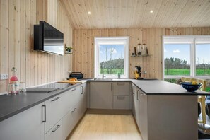 Eine moderne Küche mit Holzwänden, einem großen Fenster und Blick ins Freie.
