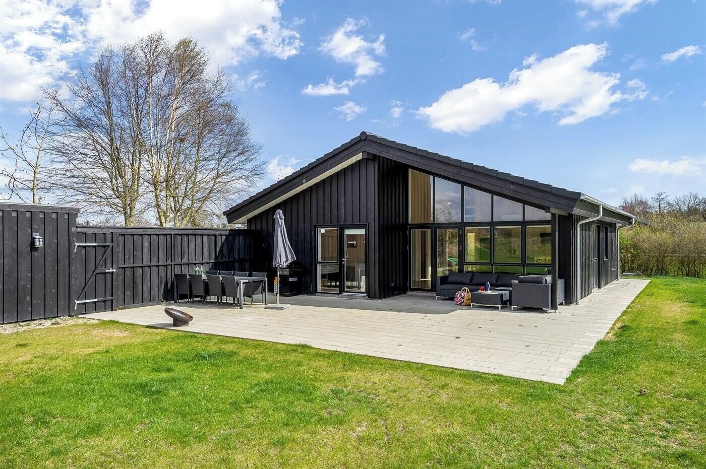 A modern house with a patio, a dining area, and a large glass door.
