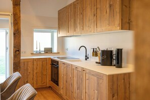 A kitchen with wooden cabinets, a sink, a dishwasher, and a window. - Relax in a thatched barn with a sauna (Ratekau)