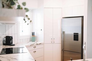Eine moderne Küche mit einem Edelstahl-Kühlschrank, weißen Schränken und einer Marmorarbeitsplatte.