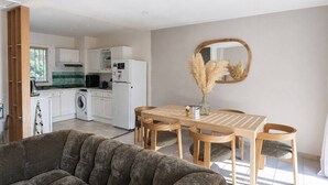 Eine moderne Küche mit weißen Schränken, einem Esstisch mit Stühlen und einem Sofa im Wohnbereich.