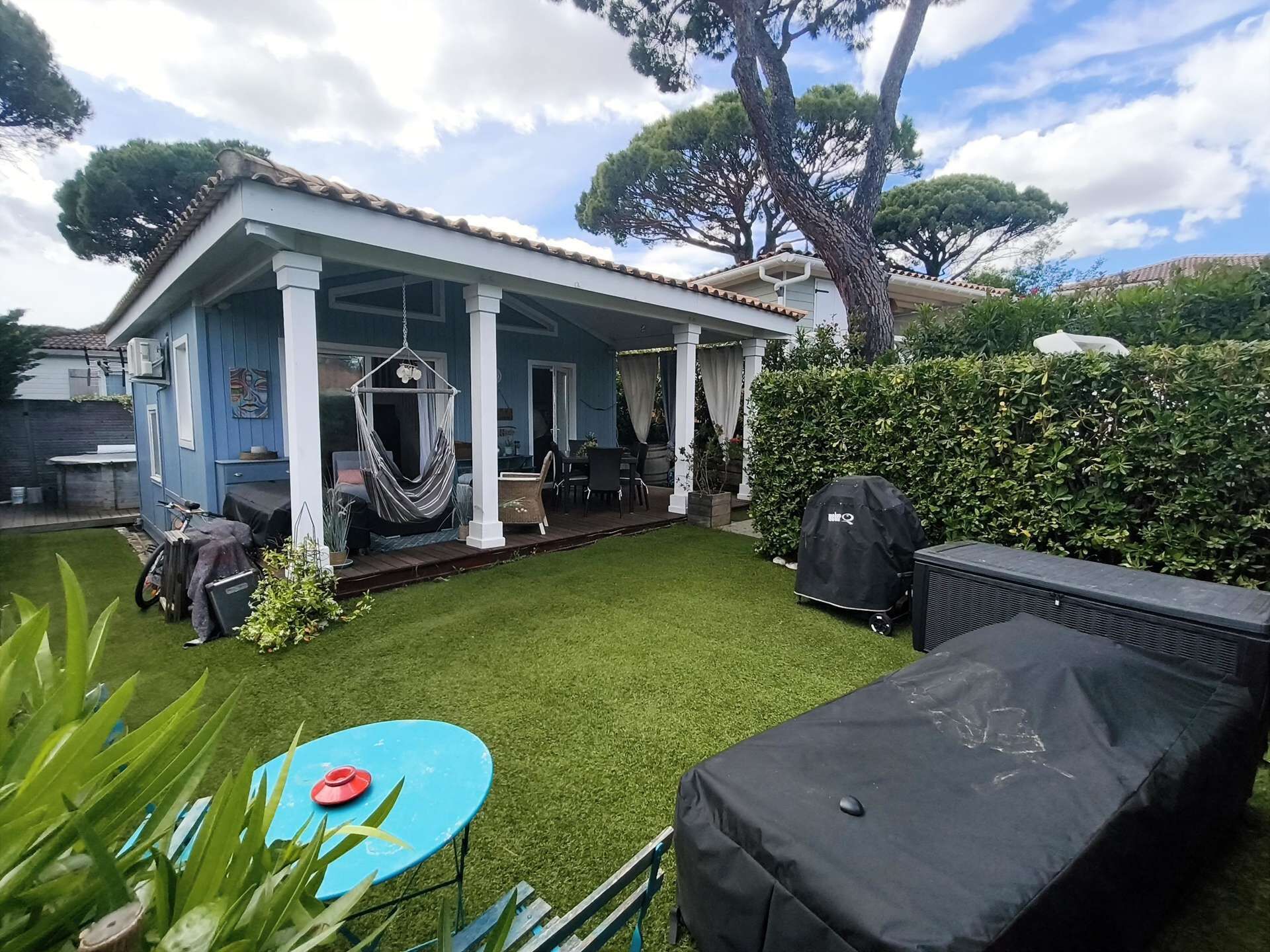 A house with a covered patio, a hammock, a barbecue grill, and a small lawn.