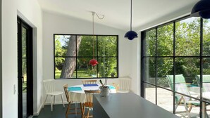 Ein moderner Essbereich mit Tisch, Stühlen und großen Fenstern.