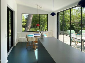 Ein moderner Essbereich mit Tisch, Stühlen und großen Fenstern.