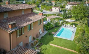 Eine Villa mit Swimmingpool, Garten und Satellitenschüssel.
